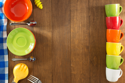 Wooden table with colorful plates and mugs